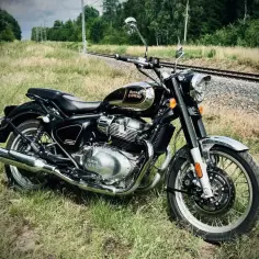 Czarny Royal Enfield Classic 650 lśni chromem przy torach kolejowych. Gotowy na podróż.