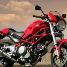 Czerwony Ducati Monster 600 z charakterystyczną kratownicową ramą, gotowy do jazdy pod zachmurzonym niebem.