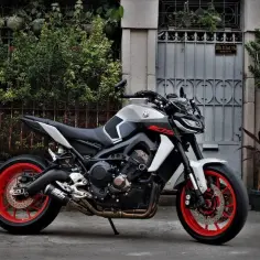 Sportowy motocykl Yamaha z czerwonymi felgami i sportowym wydechem. Wydech ma niewielką dziurę, która nadaje mu unikalny dźwięk.