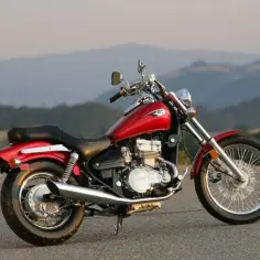 Czerwony motocykl Kawasaki EN 500 na tle gór. Idealny na spokojne przejażdżki, choć ma swoje wady i zalety.