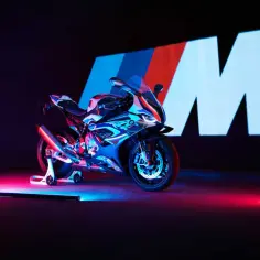 Sportowy motocykl BMW M1000R w neonowym świetle, z logo M w tle.