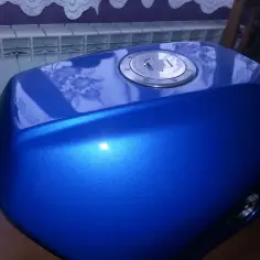 Błękitny, lśniący bak motocyklowy po malowaniu plastików. Widoczny metaliczny połysk i chromowany korek wlewu paliwa.