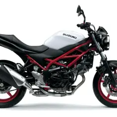 Biały motocykl Suzuki SV 650S z czerwonym stelażem i felgami, gotowy do jazdy po mieście.