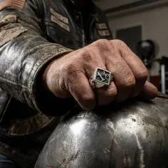 Dłoń motocyklisty w skórzanej kurtce z sygnetem "1%" symbolizującym hierarchię w klubie motocyklowym.