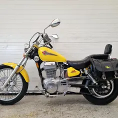 Żółty Suzuki Savage LS 650 z czarnymi sakwami i oparciem, gotowy na przygodę.