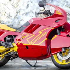 Czerwony motocykl BMW K100 z żółtymi akcentami, idealny do poznania jego bmw k100 dane techniczne.