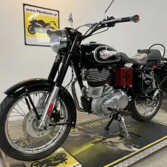 Klasyczny czarny Royal Enfield 500 z chromowanymi elementami i czerwonym krzyżem na bocznej skrzynce.