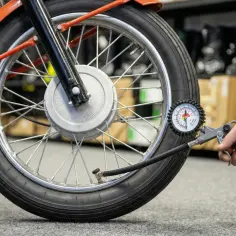 Sprawdzanie, jakie ciśnienie w oponach motocykla 125 jest optymalne, za pomocą manometru.