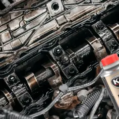 Wnętrze silnika samochodowego z widocznymi elementami i butelką płukanki K2 Motor Flush.