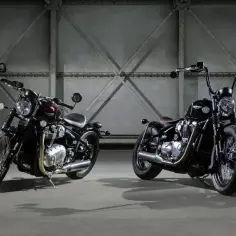 Dwa motocykle Triumph Bobber, jeden w kolorze bordowym, drugi czarny, stoją w industrialnym wnętrzu.