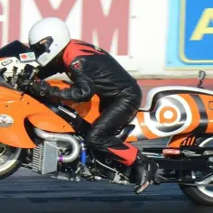 Pomarańczowy motocykl Hayabusa turbo z kierowcą w kombinezonie na torze wyścigowym.