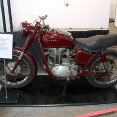 Czerwony motocykl Junak, który produkuje polska fabryka, stoi na czarnej macie.