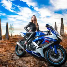 Kobieta w skórzanej kurtce i spodniach siedzi na sportowym motocyklu Suzuki. Idealny motocykl dla wysokich, gotowy na podbój świata.