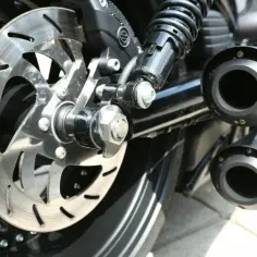 Tylne koło motocykla z tarczą hamulcową i podwójnym wydechem. Dopuszczalna głośność wydechu jest kluczowa dla komfortu jazdy.