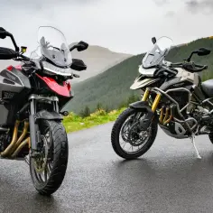 Dwa motocykle Triumph Tiger 1200 na mokrej drodze w górach. Poznajcie dane techniczne tych potężnych maszyn.