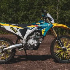 Motocykl crossowy Barton MZK 250 w kolorach niebieskim, żółtym i białym, z żółtymi szprychami.