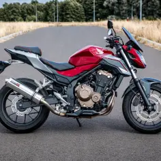 Czerwony motocykl Honda CB 500 F na drodze. Poznaj honda cb 500 f dane techniczne i możliwości tego zwinnego naked bike'a.