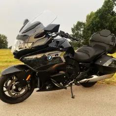 Czarny motocykl BMW K 1600 na tle łąki. Mimo swoich zalet, warto znać potencjalne bmw k 1600 wady przed zakupem.