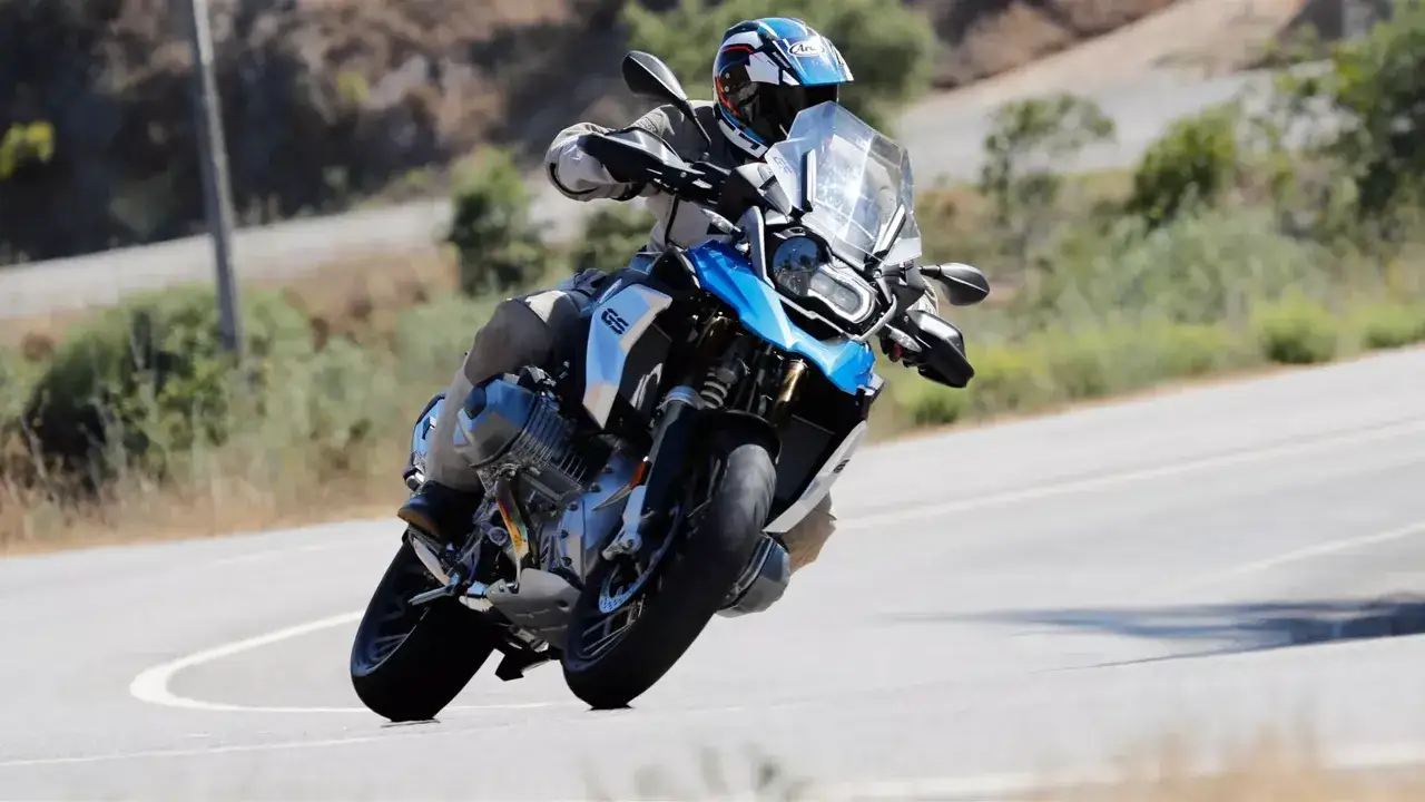 Motocyklista na BMW GS 1250 pokonuje zakręt. Mimo sporej wagi, maszyna pewnie trzyma się drogi.