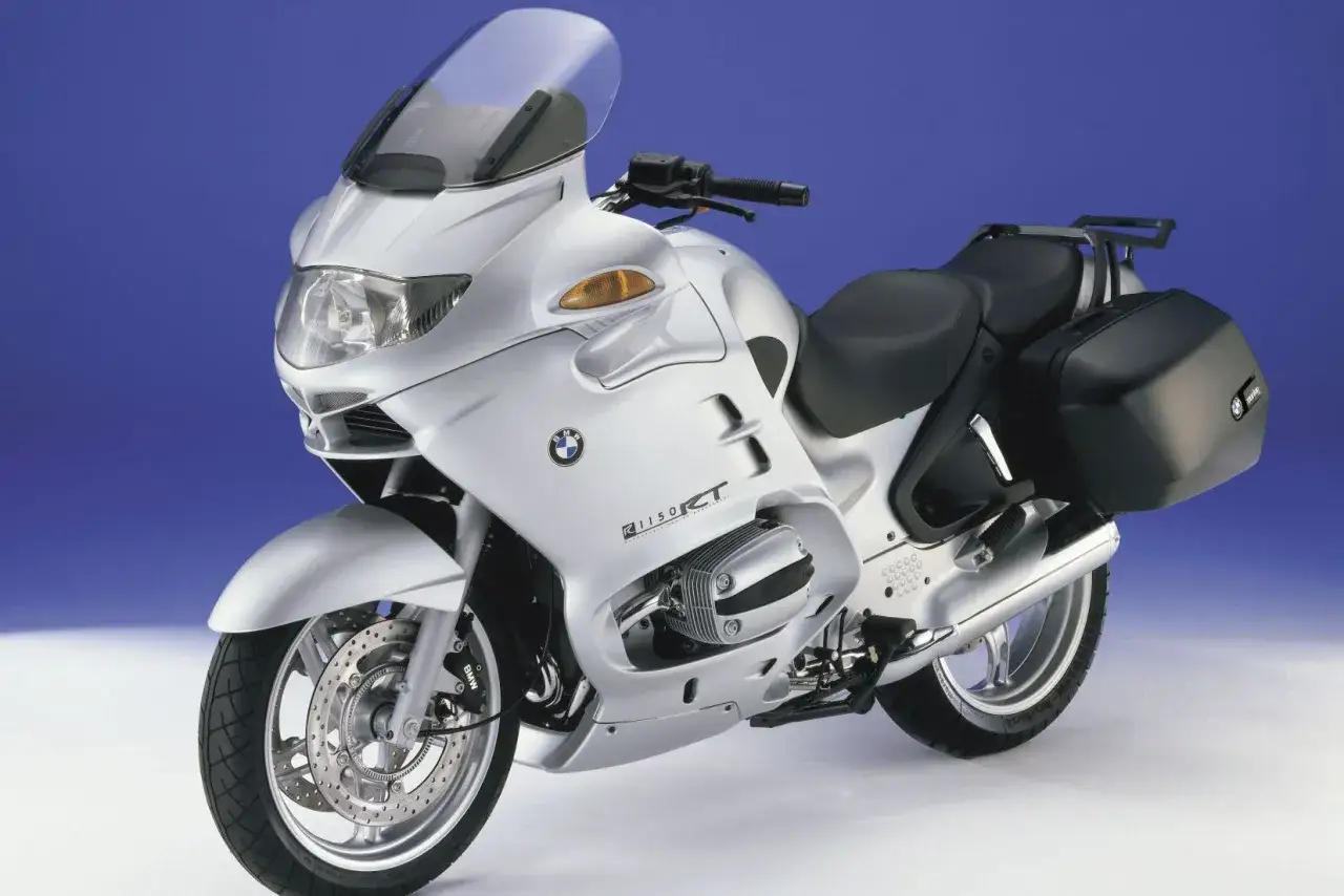 Srebrny motocykl BMW R 1150 RT z czarnymi kuframi, gotowy na dalekie podróże.