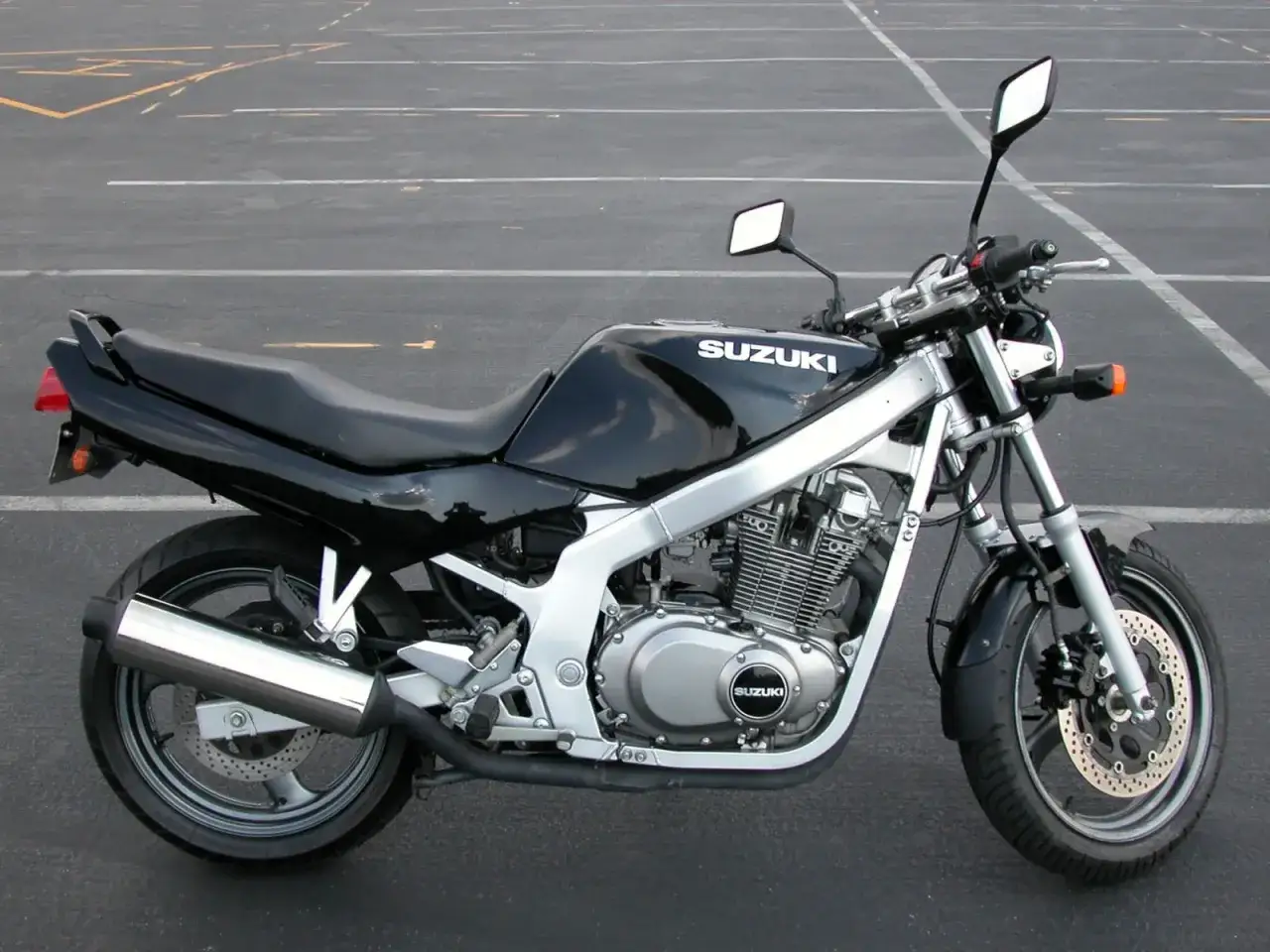 Czarny motocykl Suzuki GS 500 na parkingu. Poznaj suzuki gs 500 dane techniczne i możliwości tego klasyka.