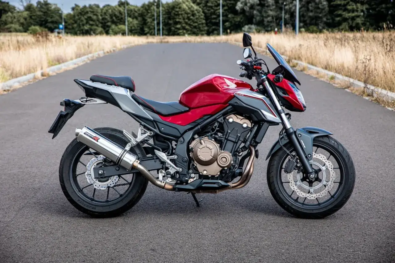 Czerwony motocykl Honda CB 500 F na drodze. Sprawdź honda cb 500 f dane techniczne, aby poznać jego możliwości.