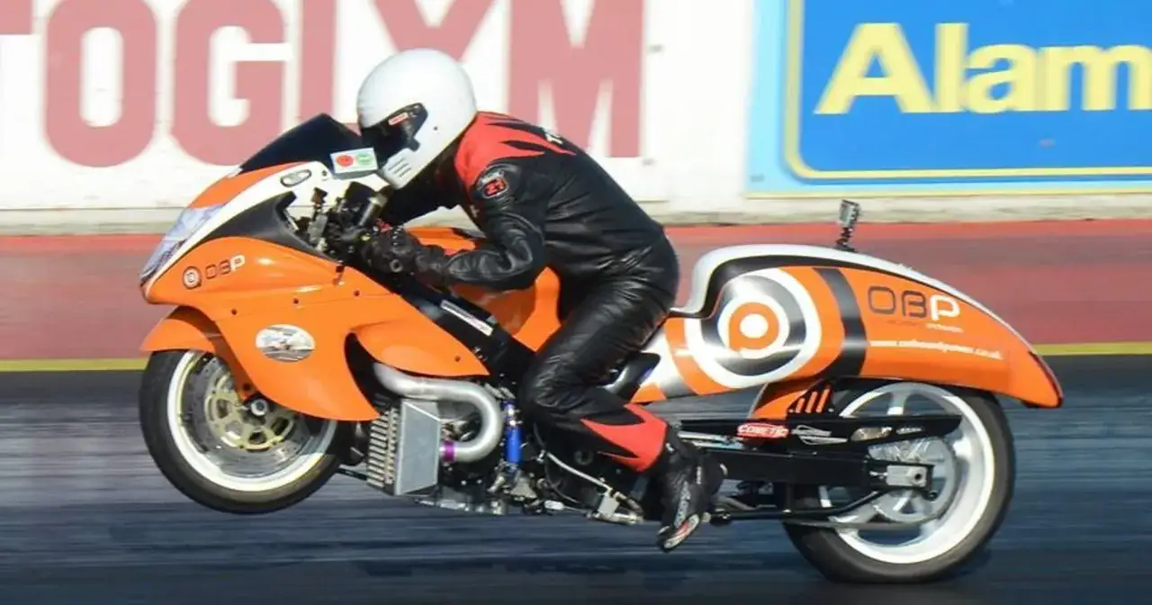 Pomarańczowy motocykl Hayabusa turbo z kierowcą w kombinezonie na torze wyścigowym.