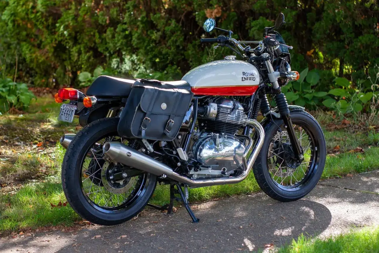 Klasyczny motocykl Royal Enfield Classic 650 w kolorze białym z czerwonym pasem, wyposażony w skórzane sakwy, gotowy na podróż.