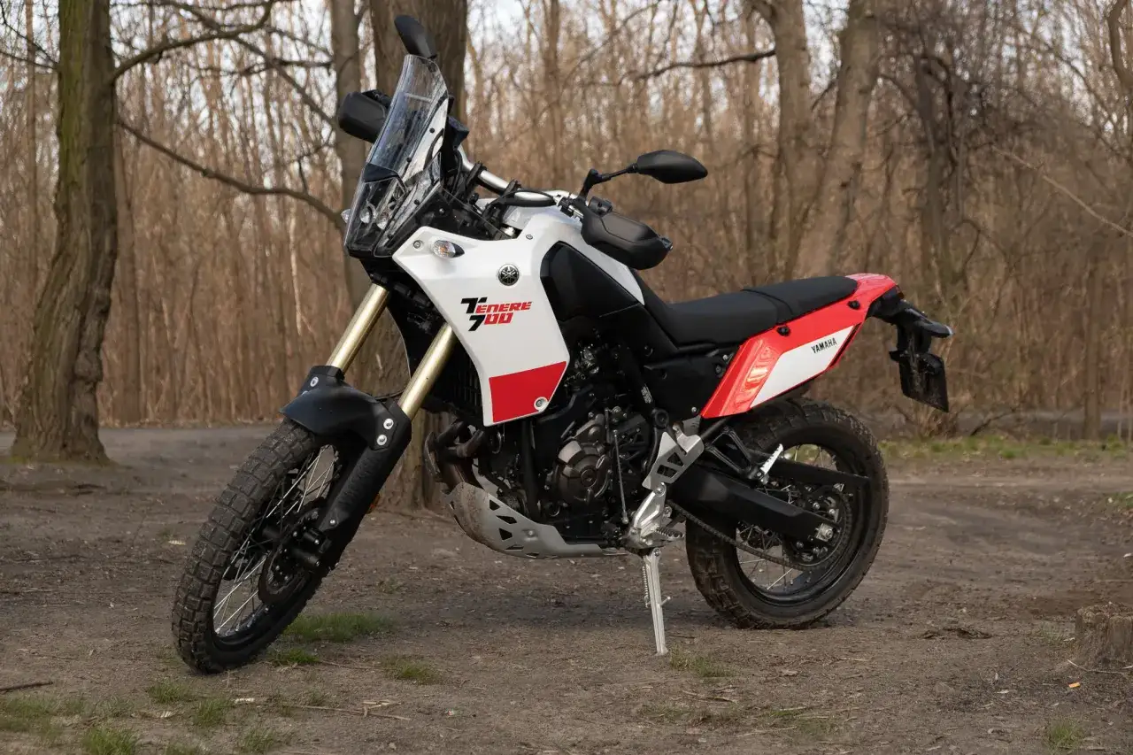 Yamaha Ténéré 700 waga: lekki motocykl adventure gotowy na teren. Biało-czerwona maszyna stoi na leśnej ścieżce.