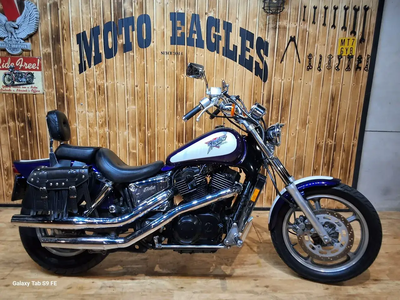 Fioletowo-biały motocykl Honda Shadow 1100, z sakwami i oparciem. Idealny do podróży, sprawdź honda shadow 1100 dane techniczne.