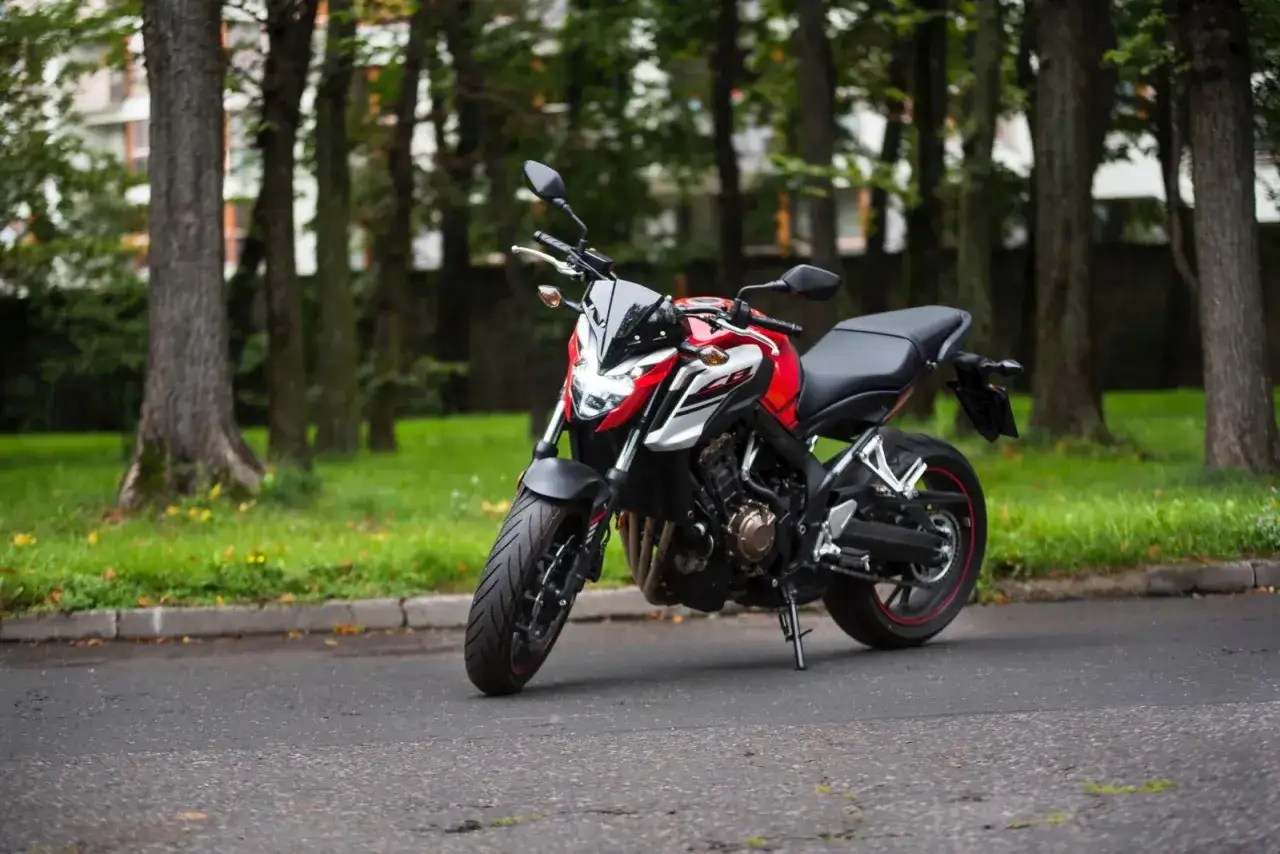 Czerwono-biały motocykl Honda CB650F na tle drzew. Warto sprawdzić honda cb650f dane techniczne przed zakupem.