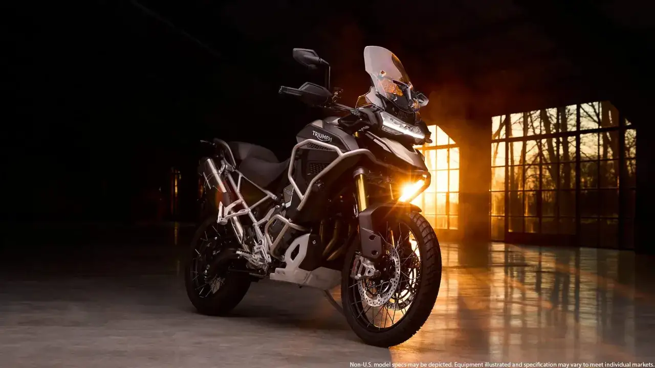 Triumph Tiger 1200 w mrocznym wnętrzu, z ciepłym światłem wpadającym przez okna. Dane techniczne tego motocykla budzą podziw.
