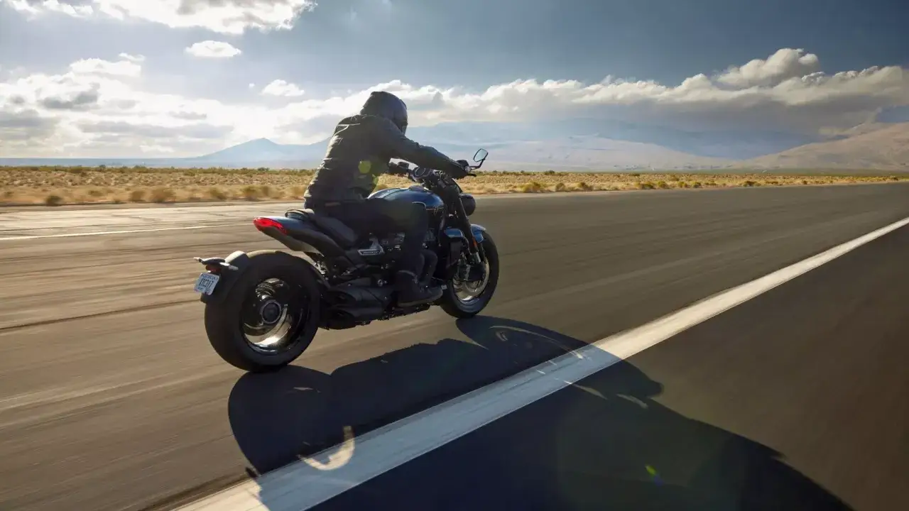 Motocyklista na Triumph Rocket 3, odkrywający jego imponujące dane techniczne podczas jazdy po pustej drodze.