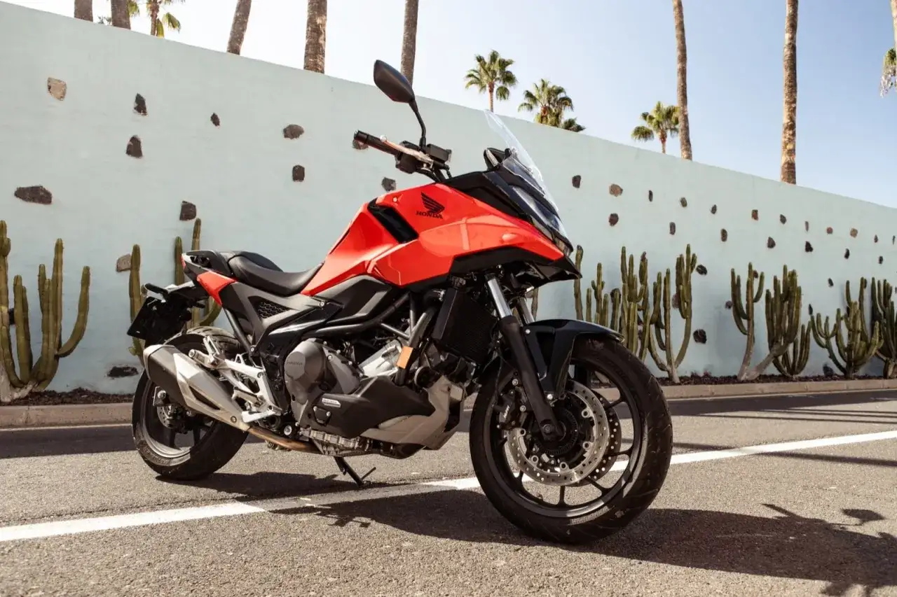 Czerwona Honda NC750X na tle ściany z kaktusami i palmami. Poznaj jej honda nc750x dane techniczne.