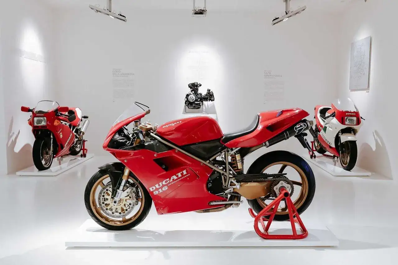 Czerwone Ducati 916, ikona designu, prezentowane w muzeum obok innych modeli.