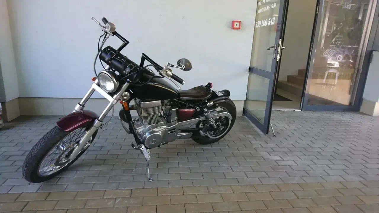 Suzuki Savage z czarnym zbiornikiem i brązowym siedzeniem, gotowy do jazdy.