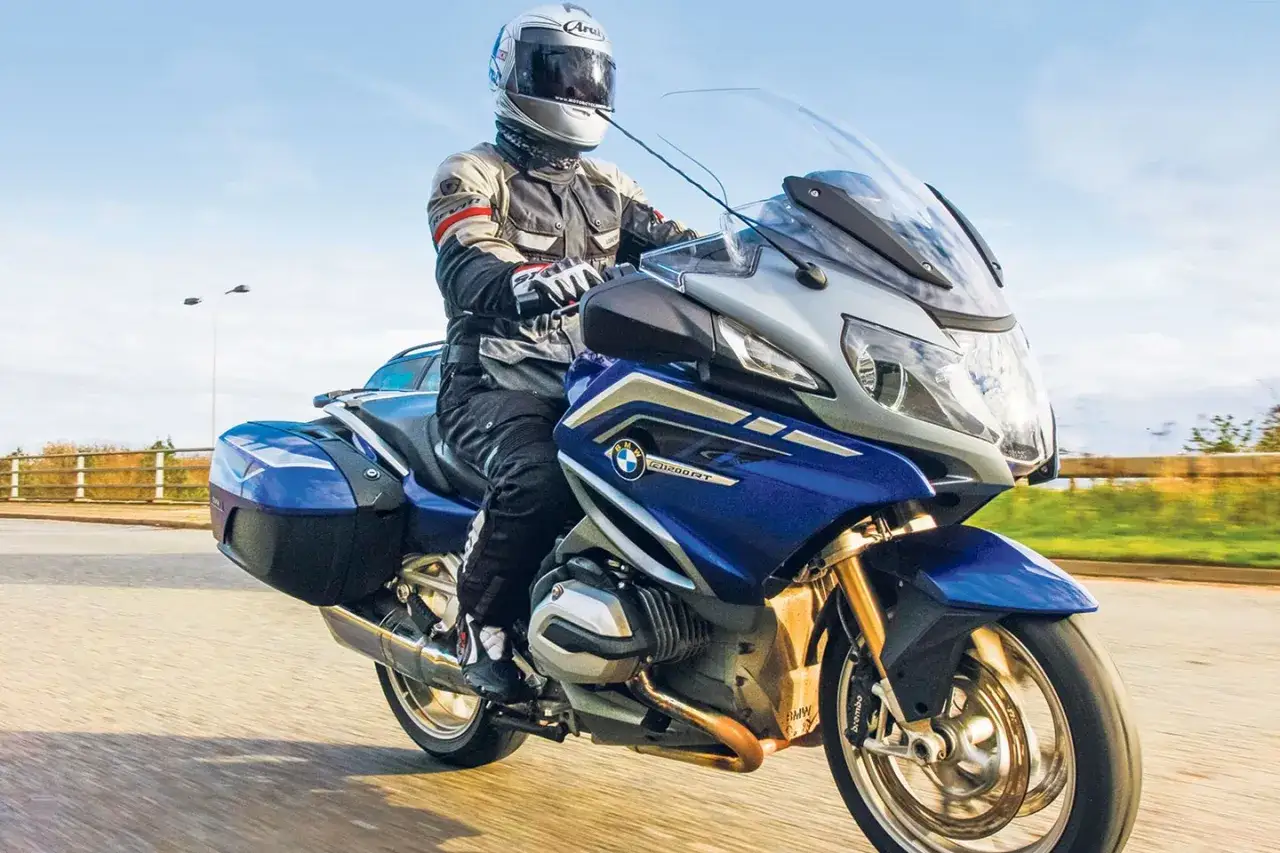 Motocyklista w kasku i kombinezonie jedzie niebieskim BMW R 1200 RT. Poznaj dane techniczne tego turystycznego motocykla.