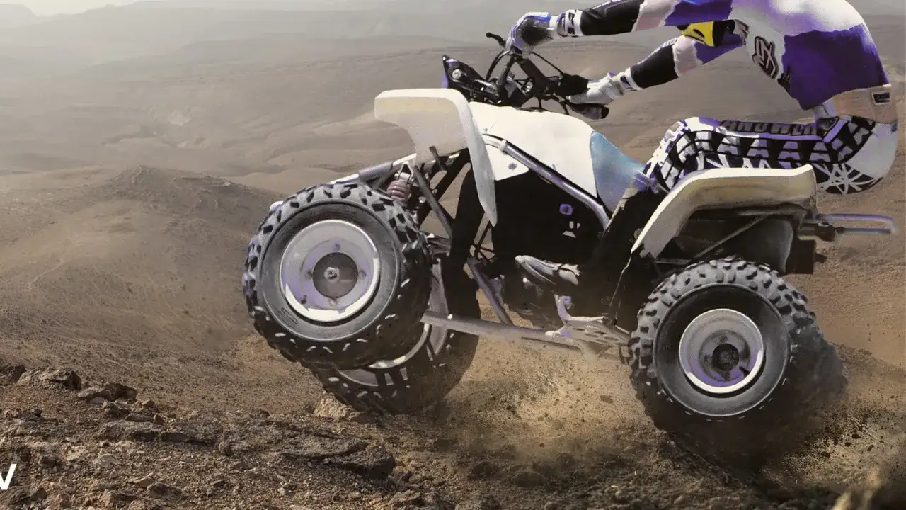 Kierowca w stroju terenowym szaleje na Yamaha Blaster 250 po pustynnym terenie, wzbijając tumany kurzu.