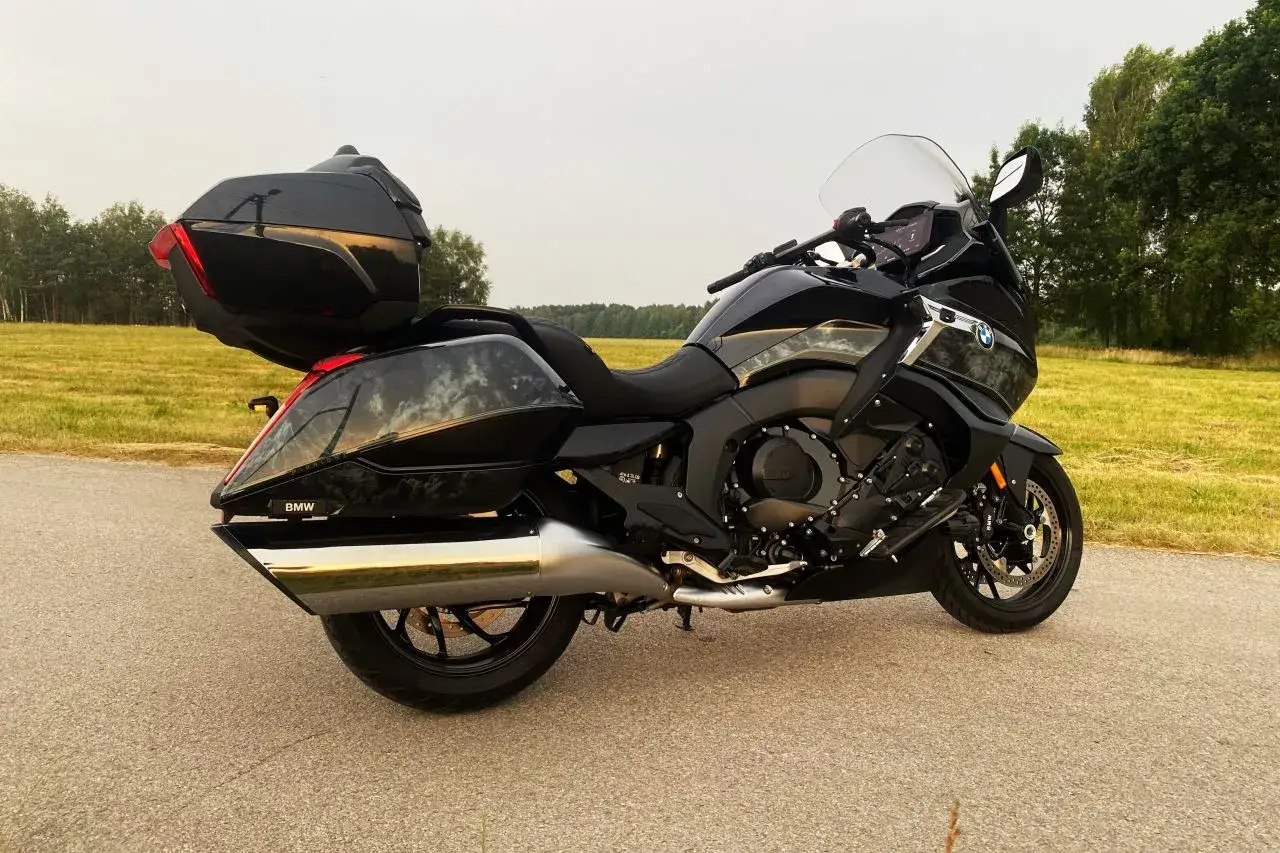 Czarny motocykl BMW K 1600 na tle łąki. Choć piękny, jego wady mogą być widoczne w szczegółach.