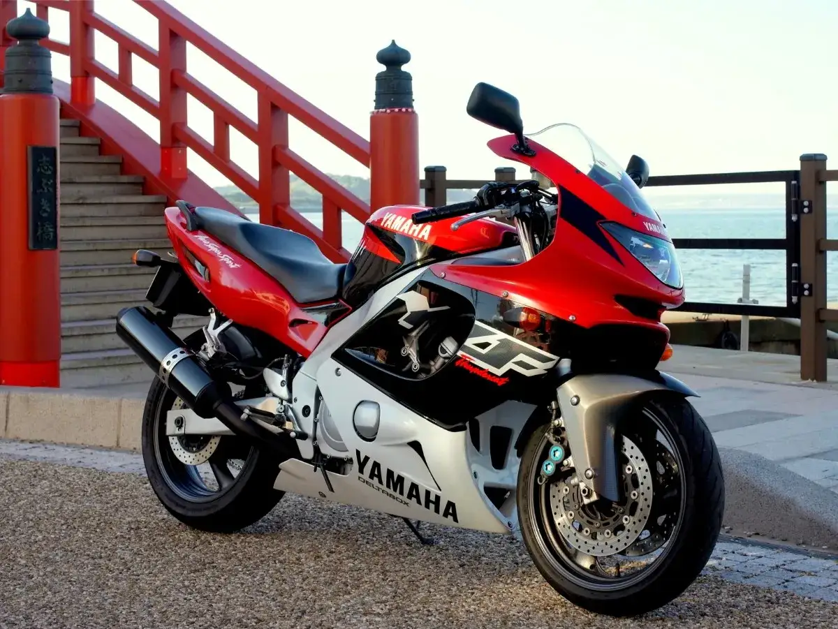 Czerwony motocykl Yamaha Thundercat 600 na tle japońskiego mostu i morza.