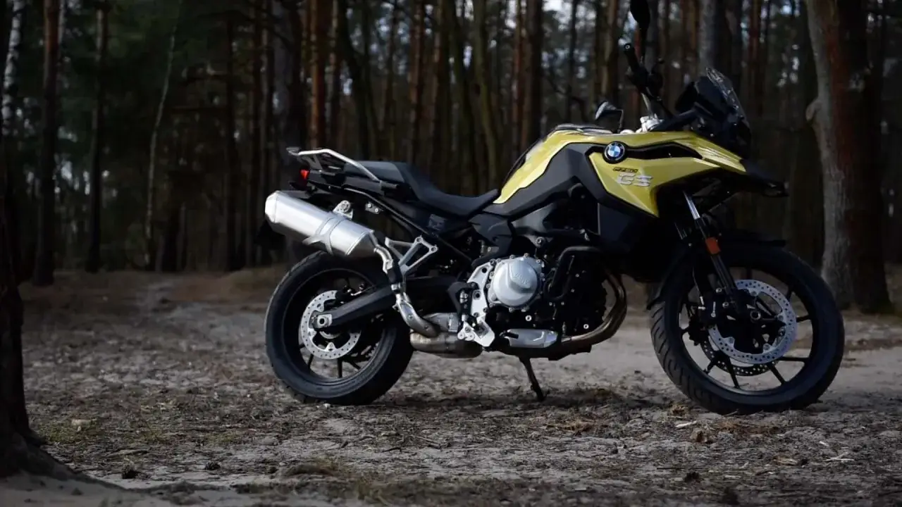 Żółty motocykl BMW F 750 GS w lesie. Poznaj jego dane techniczne i możliwości terenowe.