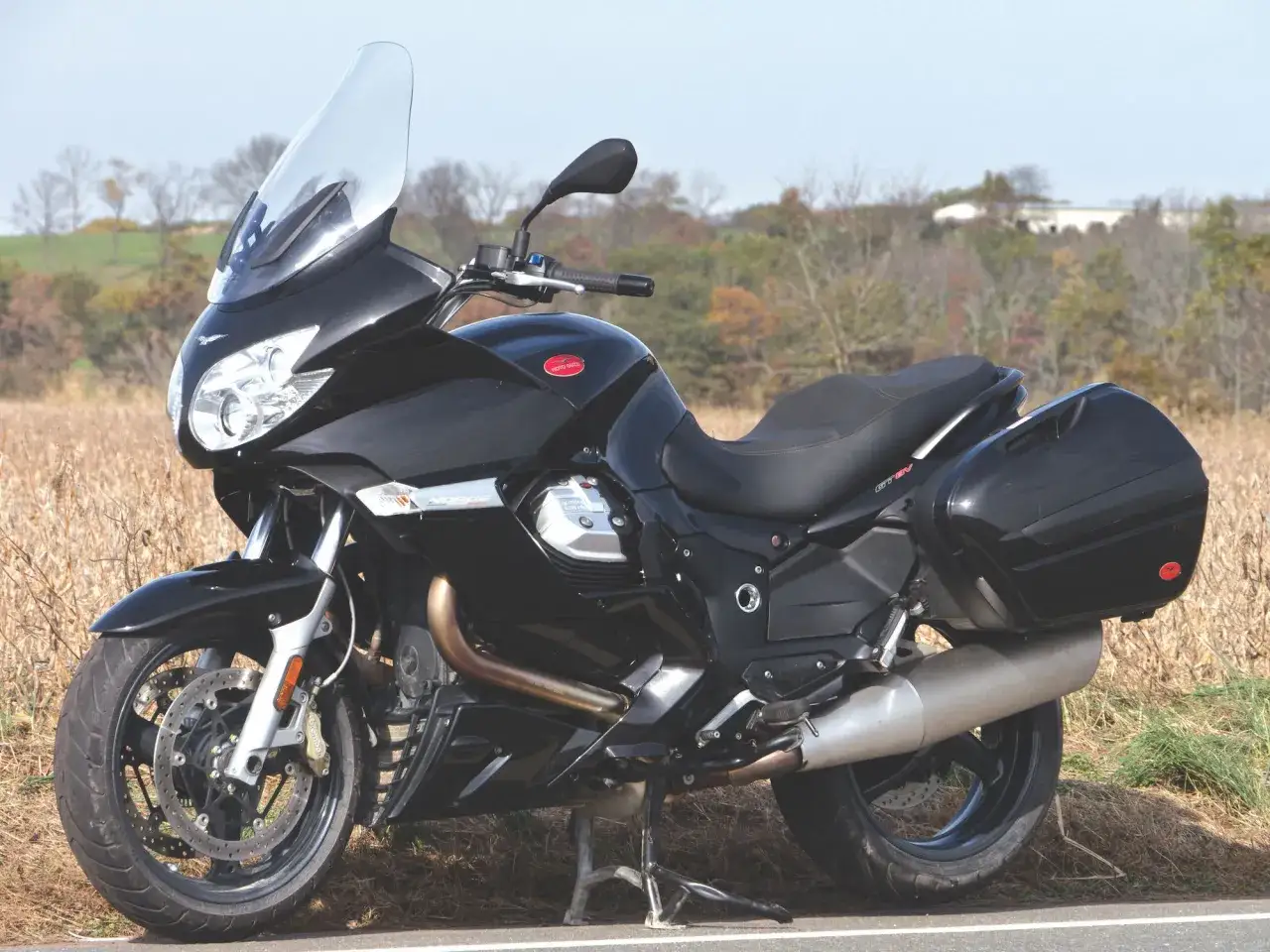 Czarny motocykl Moto Guzzi Norge z kuframi, gotowy na podróż przez jesienne krajobrazy.
