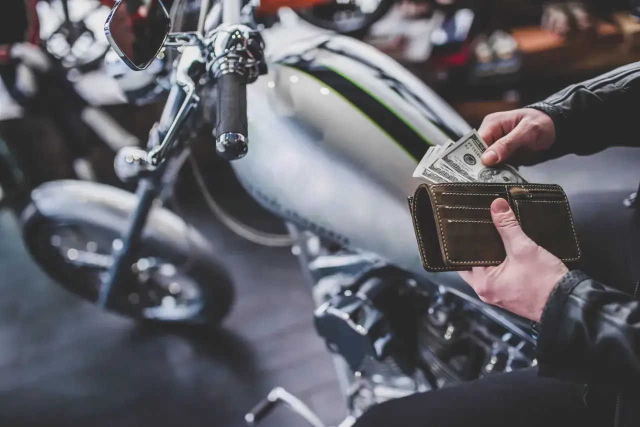 Ręce wyciągają pieniądze z portfela, by kupić wymarzony chopper do 20 tys.