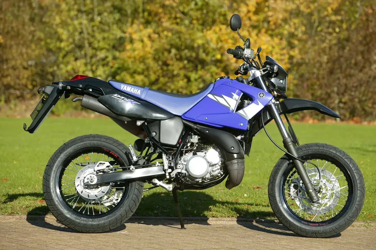 Niebieski motocykl Yamaha DT 125 na trawie, idealny do poznania jego danych technicznych.