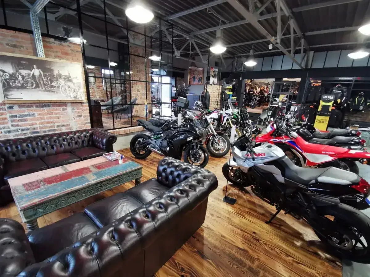 W salonie motocyklowym czeka nowy motocykl Suzuki. W tle inne maszyny i skórzane kanapy.
