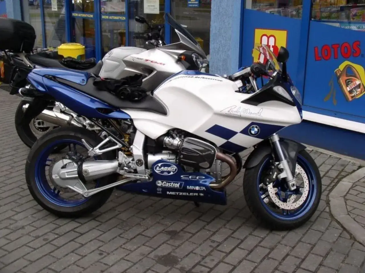Biało-niebieski motocykl BMW R1100S z charakterystyczną szachownicą i podpisem na baku.