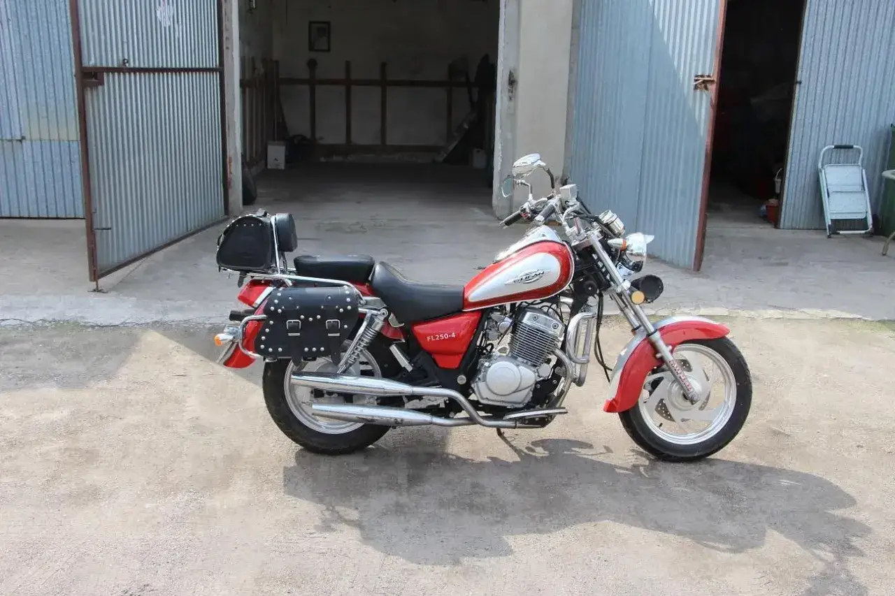 Czerwony motocykl Lifan 250 z sakwami i bagażnikiem, gotowy do podróży.