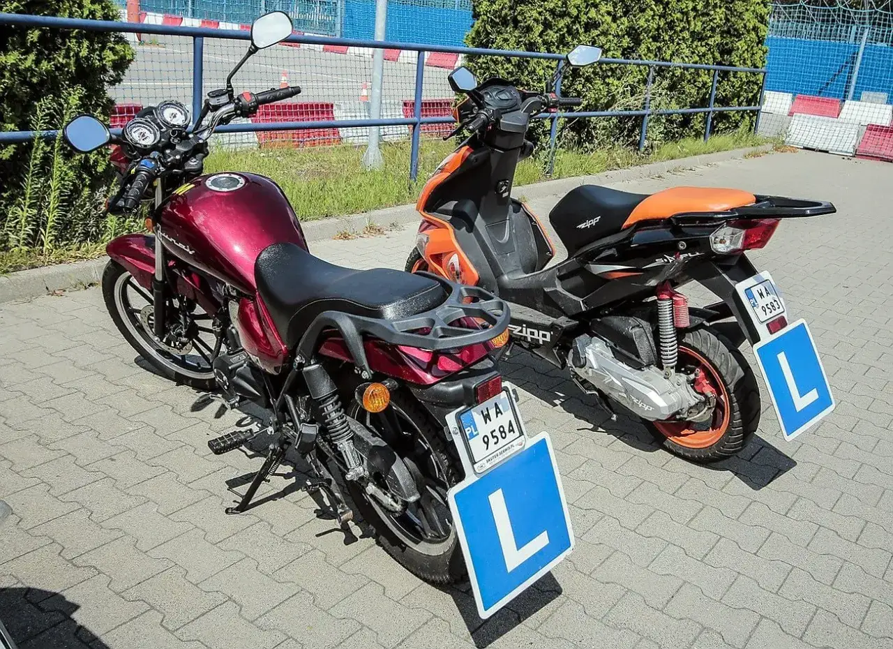 Dwa pojazdy, motor i skuter, z tabliczkami 