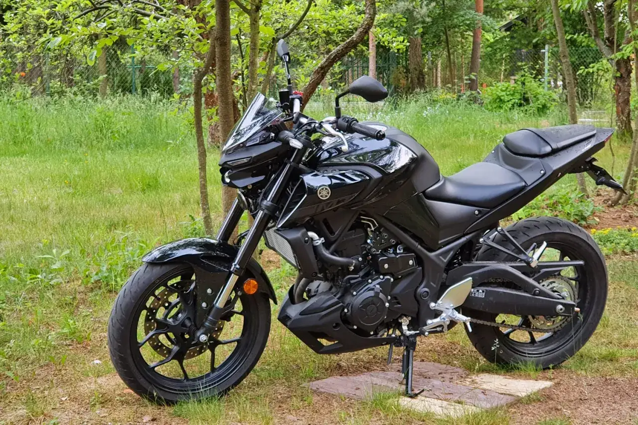 Czarny motocykl Yamaha MT-03 660, gotowy na przygodę wśród zieleni.