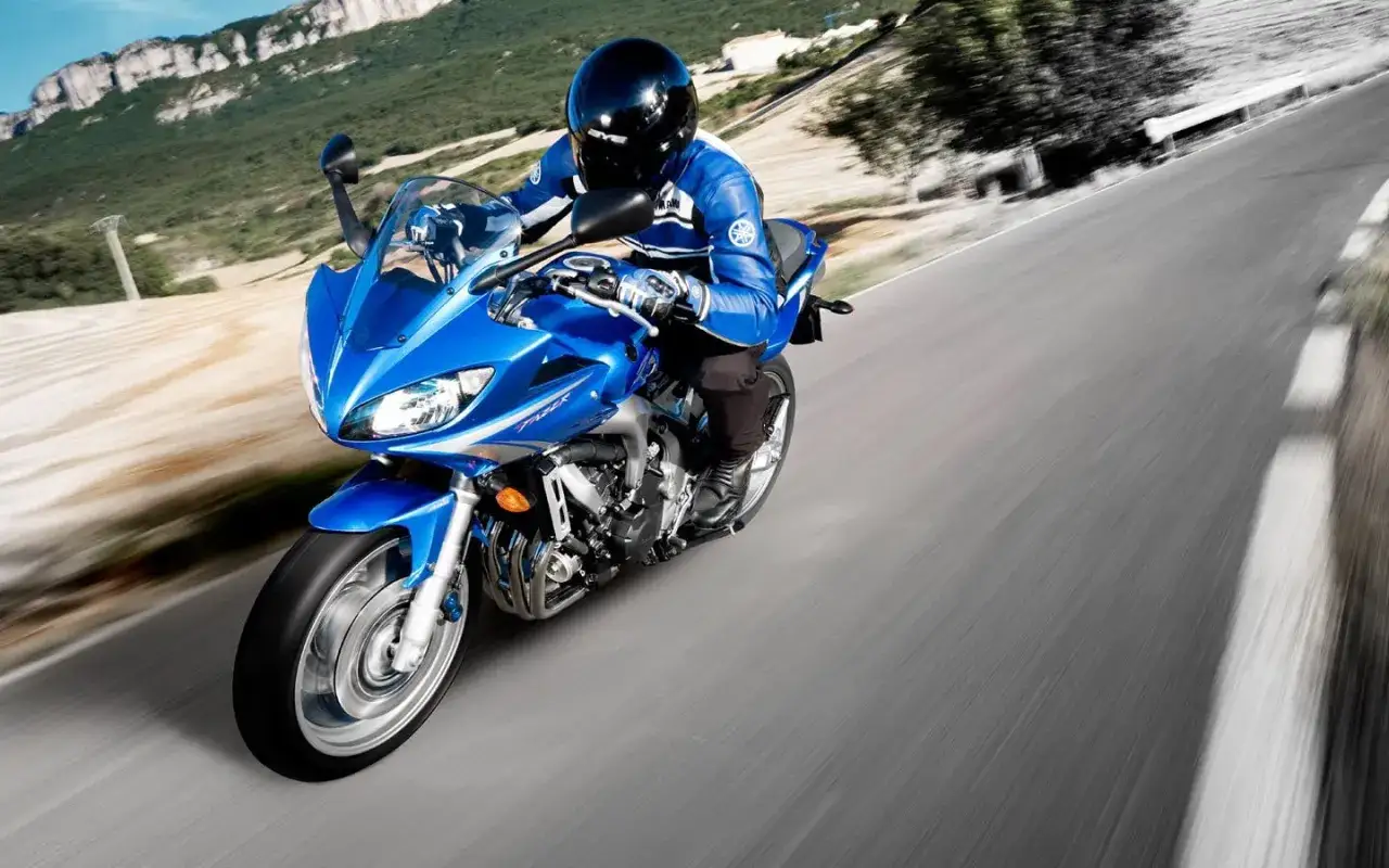 Motocyklista w niebieskim kombinezonie na sportowym motocyklu Yamaha FZ6, pędzący po krętej drodze. Poczuj moc i przyspieszenie 0-100!
